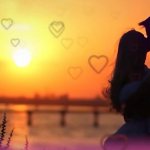 Silhouettes of a kissing guy and a girl against the backdrop of the rising sun and contour hearts