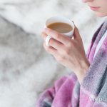 woman with a cup of coffee wrapped in a blanket